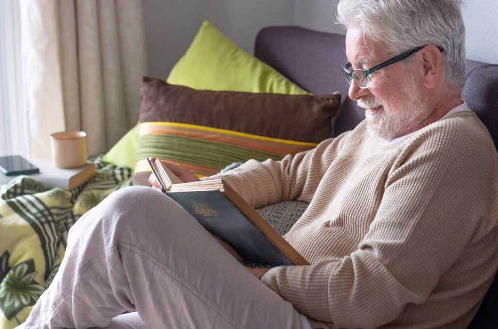 Elderly man reading a book home - indoor activities for seniors