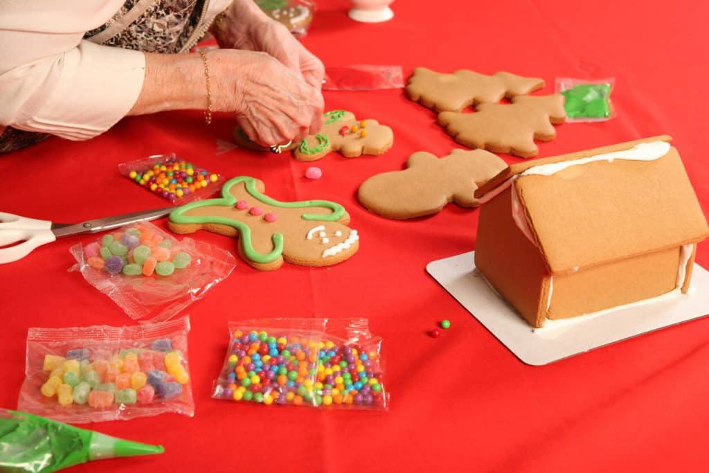 Senior woman making and decorating gingerbread houses and Christmas cookies. Christmas activities for seniors