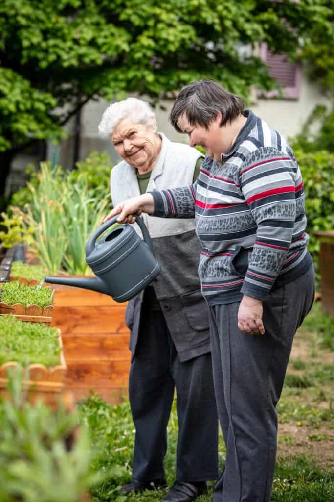 Senior adult women watering the garden with a watering can, activities for seniors with cognitive impairment