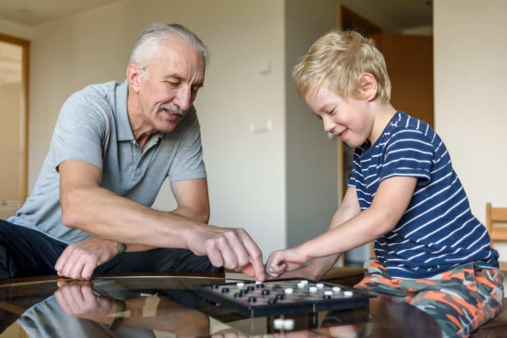 Grandfather and grandson playing a game of checkers together, easy activities for seniors with dementia