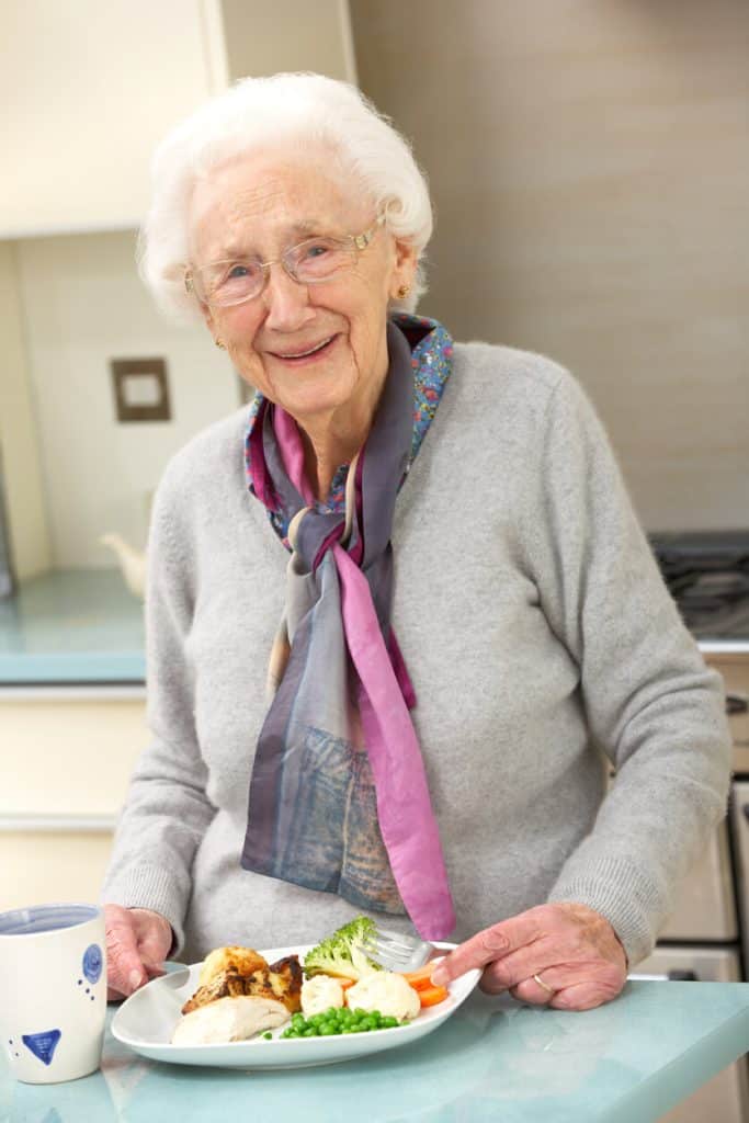 Senior woman happily eating a nutritious meal. assisted living menus