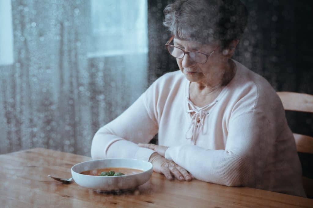 Senior resident woman staring sadly at bowl of soup. assisted living menus