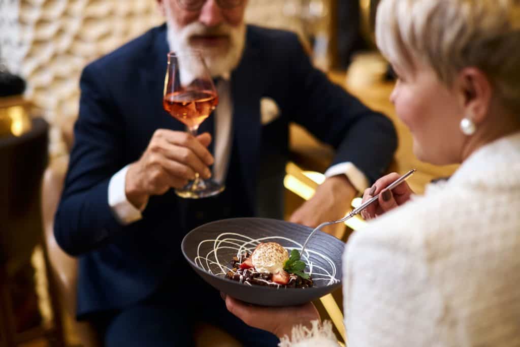 Bearded mature senior man enjoying high end dining, luxurious assisted living