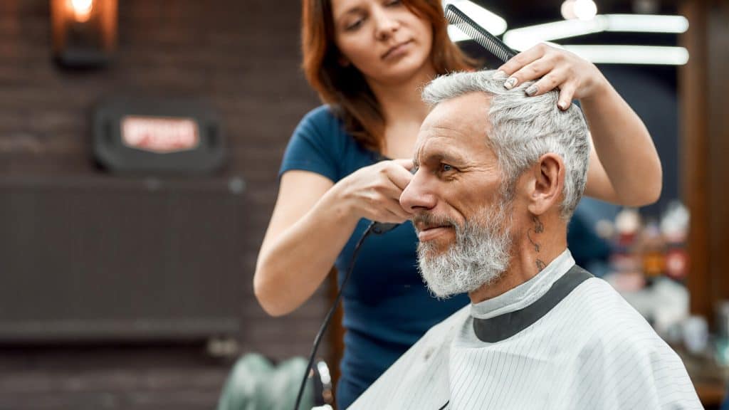 Happy senior man getting a stylish haircut at a salon, luxurious assisted living