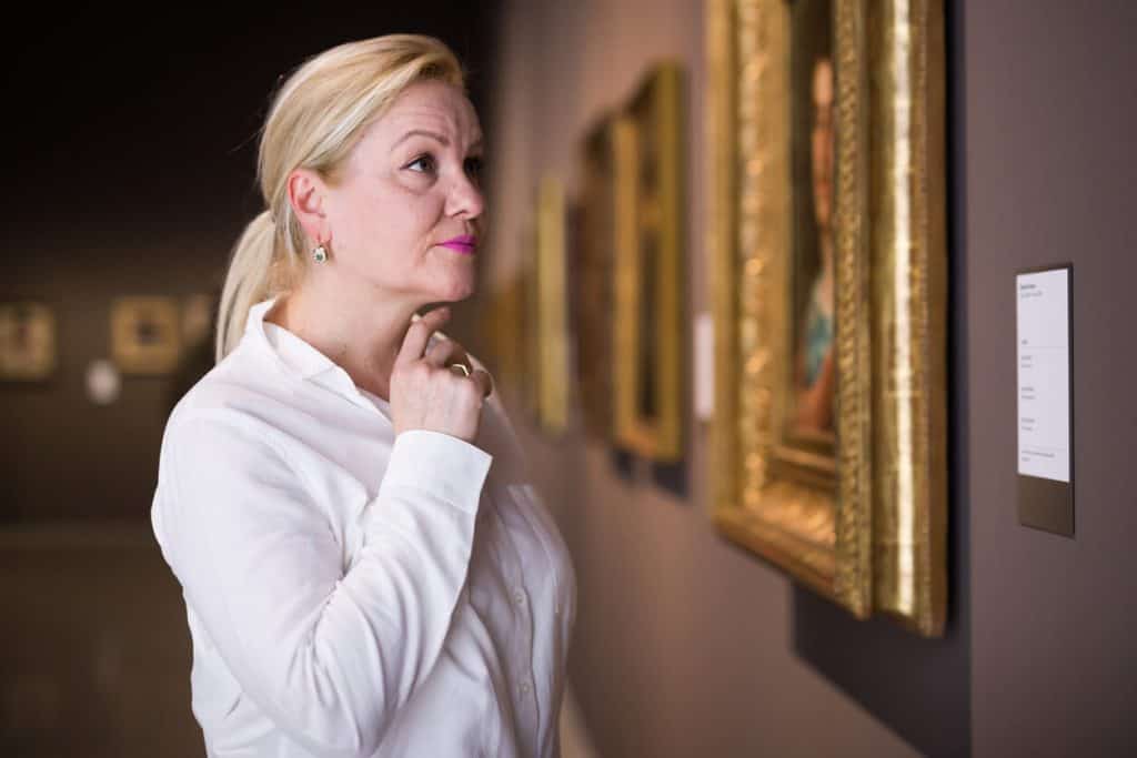 Mature senior woman looking at paintings in an art gallery, luxurious assisted living
