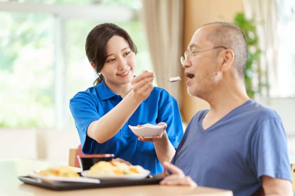 Caregiver at assisting a senior man with meals, assisted living in reno