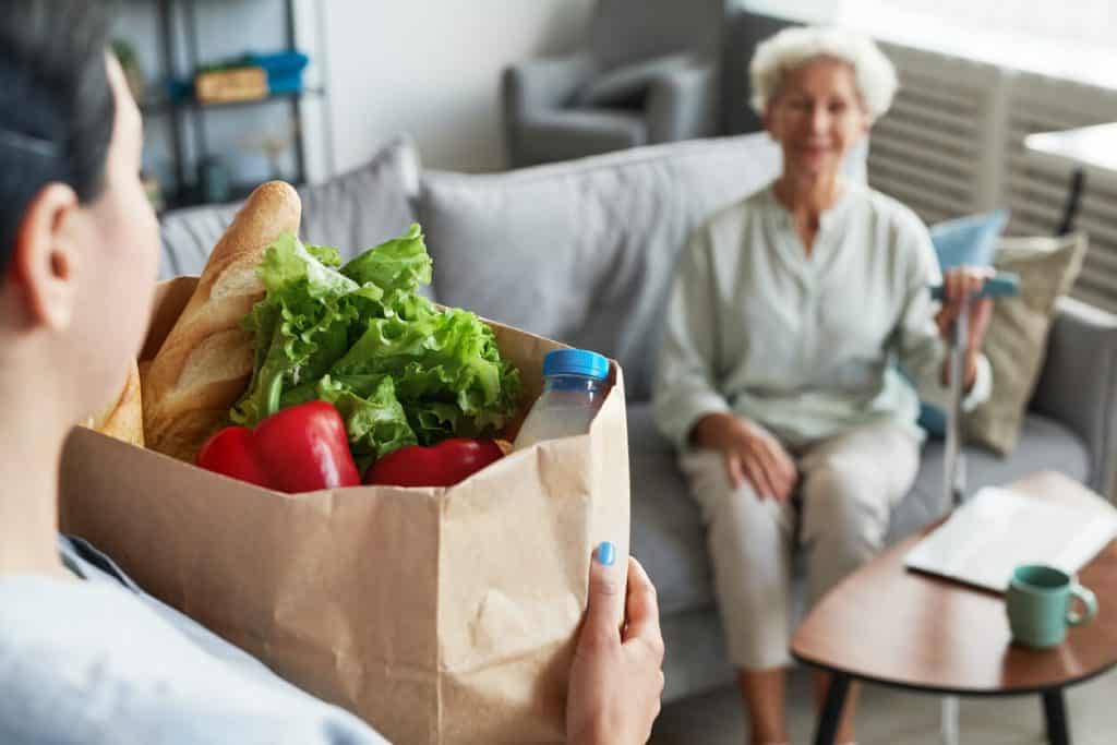 Caregiver delivering groceries to an elderly woman at home, assisted living in reno