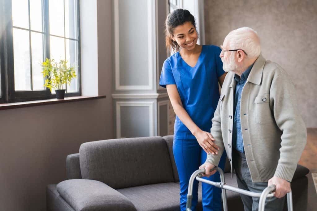 young caregiver helping an elderly man to walk at home, assisted living in reno