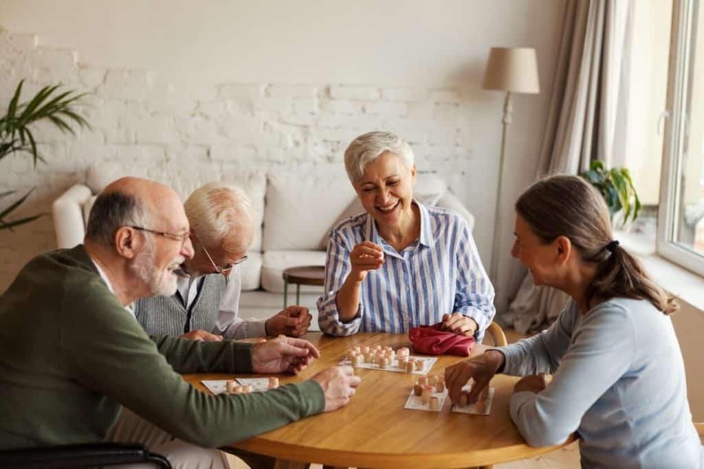 Two senior women and two senior men happily playing bingo, assisted living with memory care supported service group homes