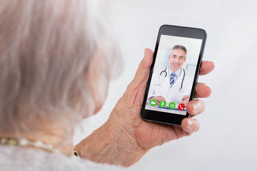 older senior woman using smart phone for a telehealth appointment with doctor, home care for elderly in their own homes