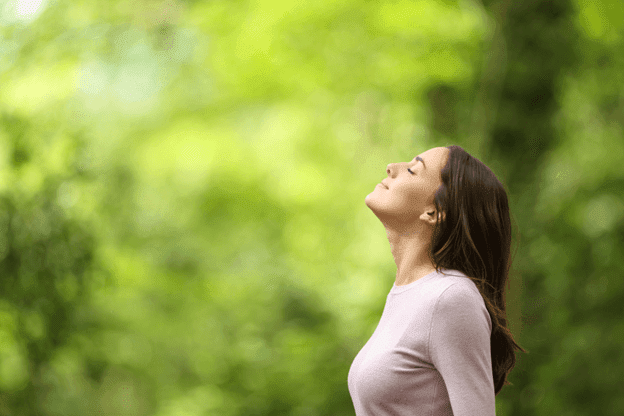 Content, relaxed female nurse standing and practice meditating outdoors, home health aides