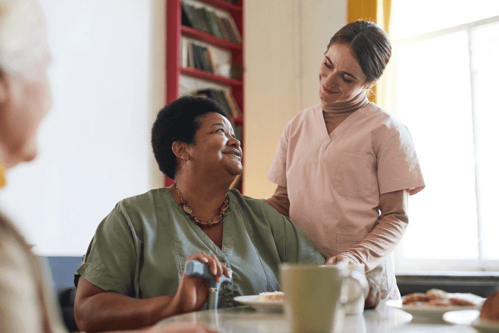 view of female home care aide bonding with elderly woman at dinner