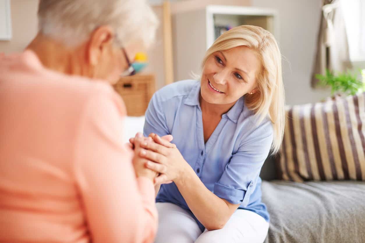 Mature woman and older woman talking on the couch, moving into assisted living checklist
