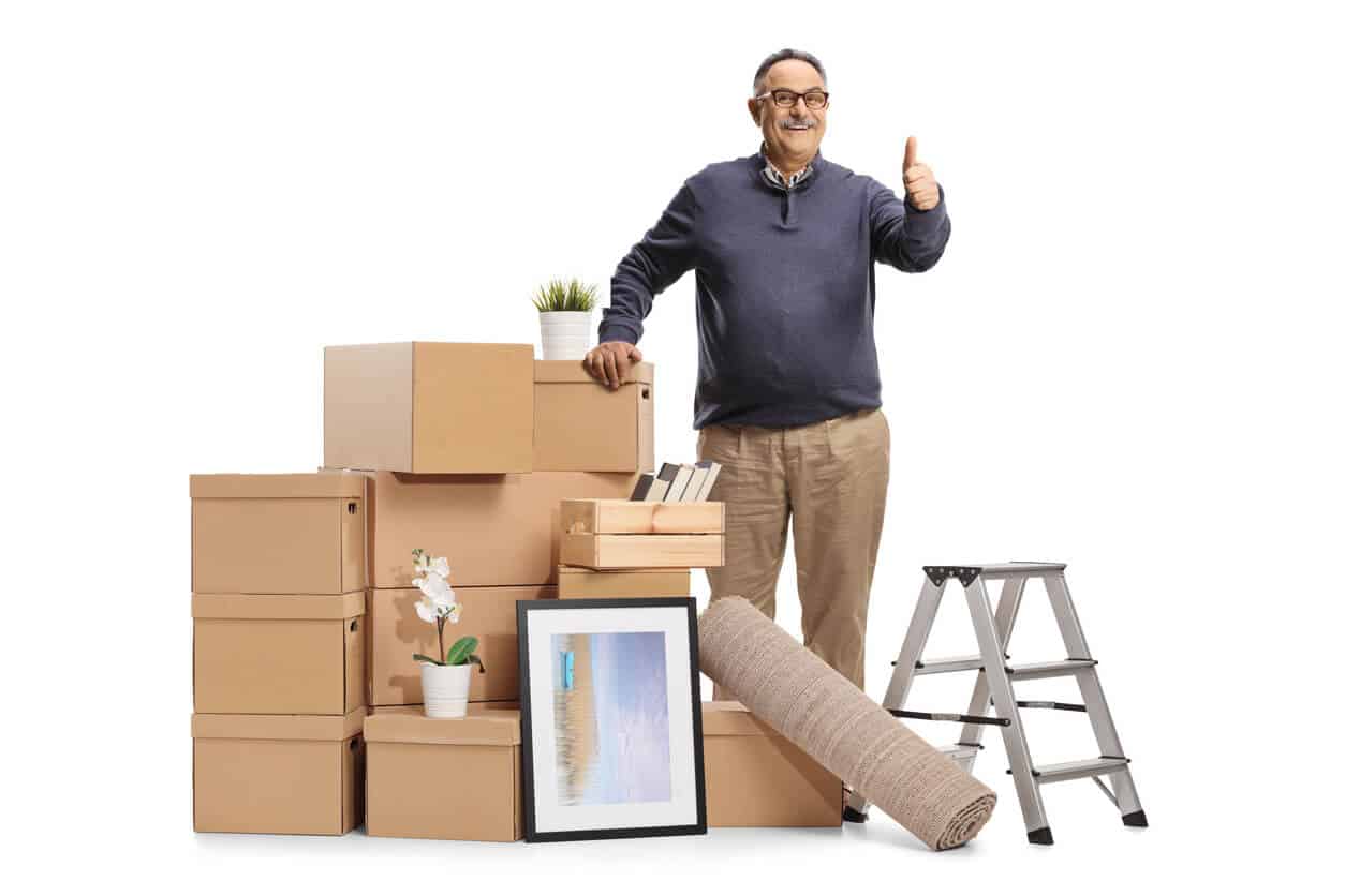 Senior man standing next to a pile of packed boxes