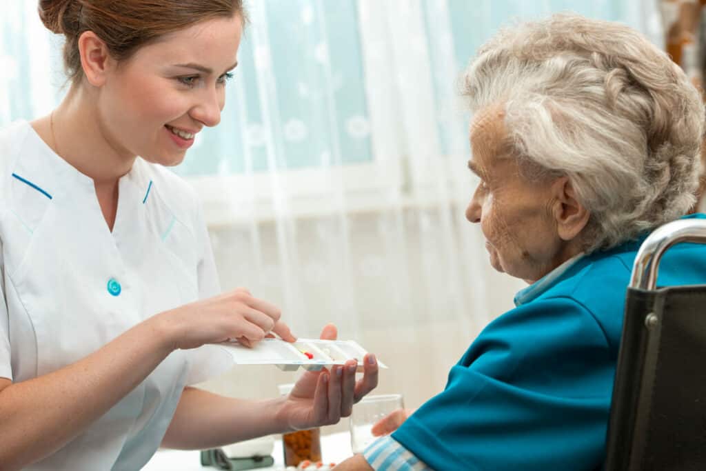 home care private nurse giving a senior woman her pills -private nurses near me