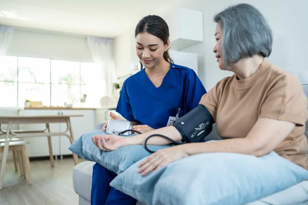 A Registered Nurse checking the blood pressure of the older woman - in-home senior care jobs