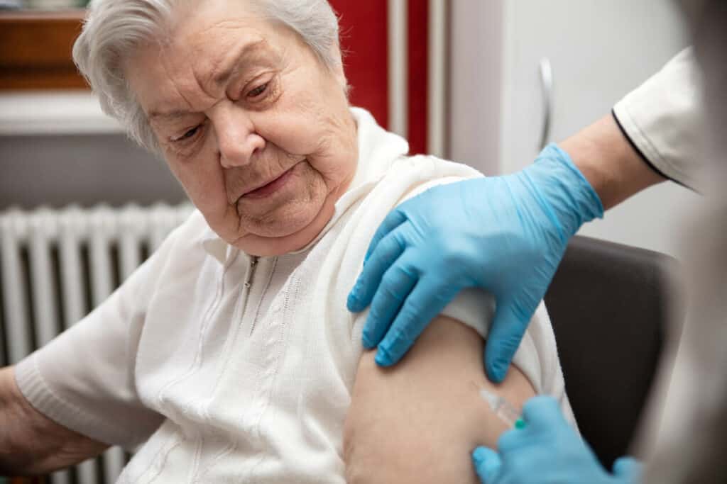 nurse giving an elderly woman a covid-19 immunization vaccine |home nurse care near me