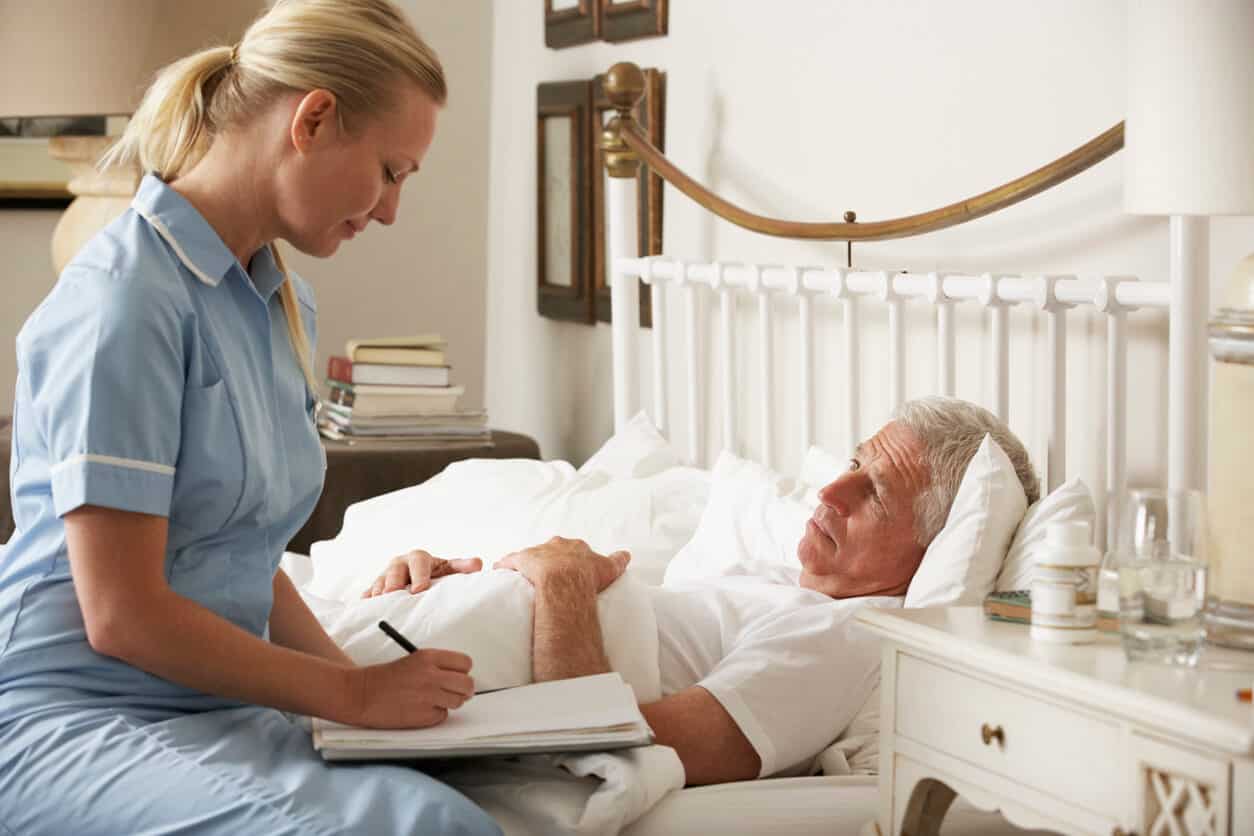 A caregiver providing home health aide service of health monitoring to a senior male patient