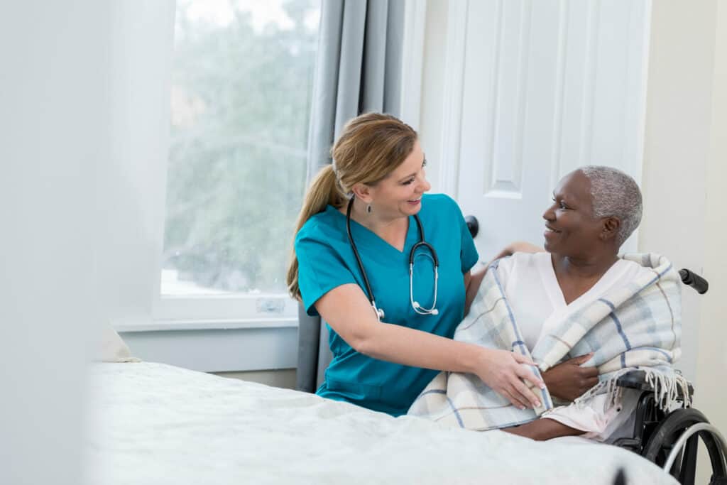 Nurse wrapping a senior patient in a plaid blanket with care