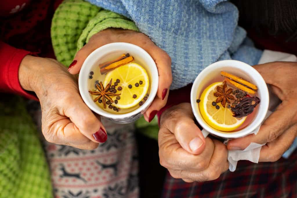 Two cups of herbal tea with floating herb leaves in the tea.