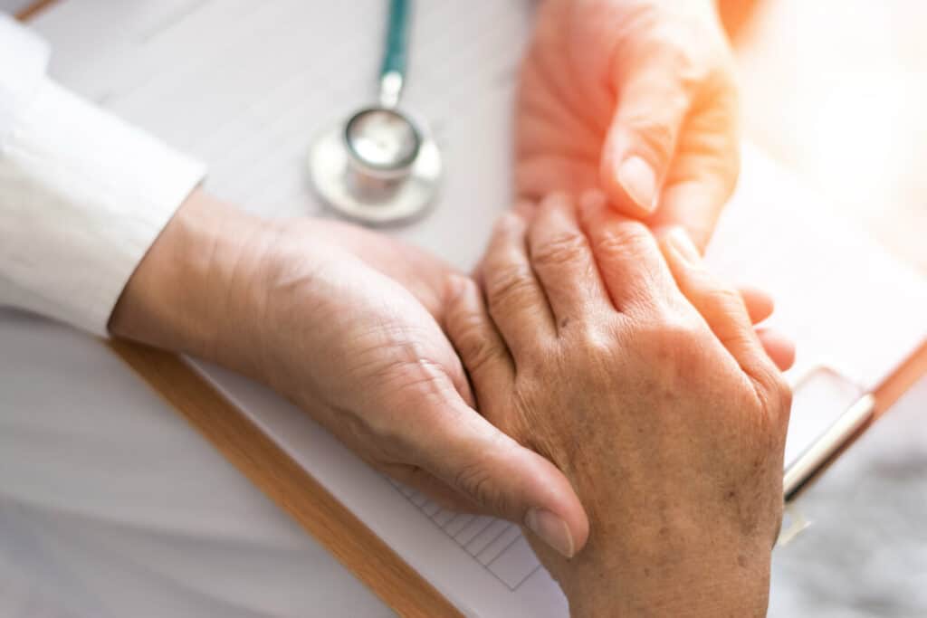 A gerontologist holding the hand of an older adult