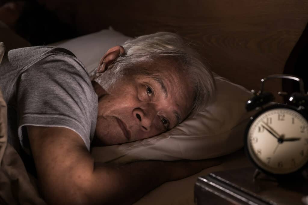 how much sleep do over 60s need? | senior Asian woman frustrated and unable to sleep at night