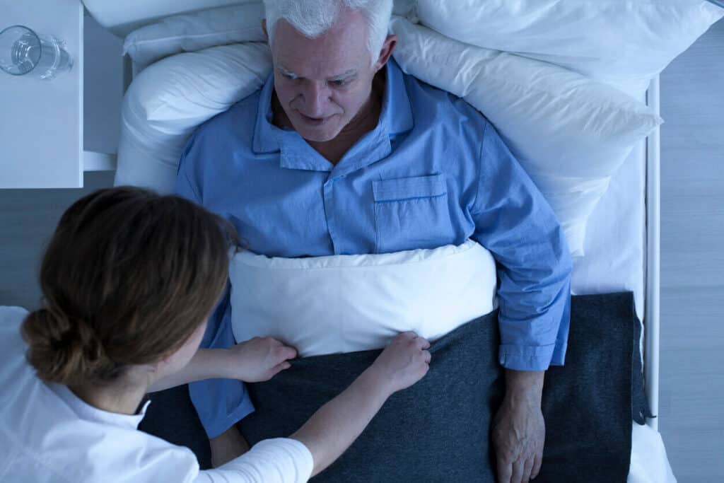 how much sleep does an 80 year old need? | in-home caregiver tucking in a senior man at night