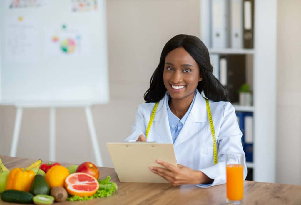 Questions to ask a female nutritionist include if they have a degree or are certified or licensed. A photo of a female nutritionist creating a meal plan for the patient.