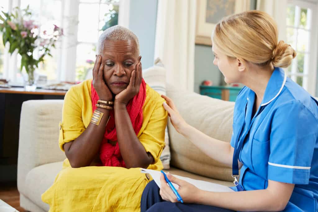 elder social worker counseling an elderly woman at home