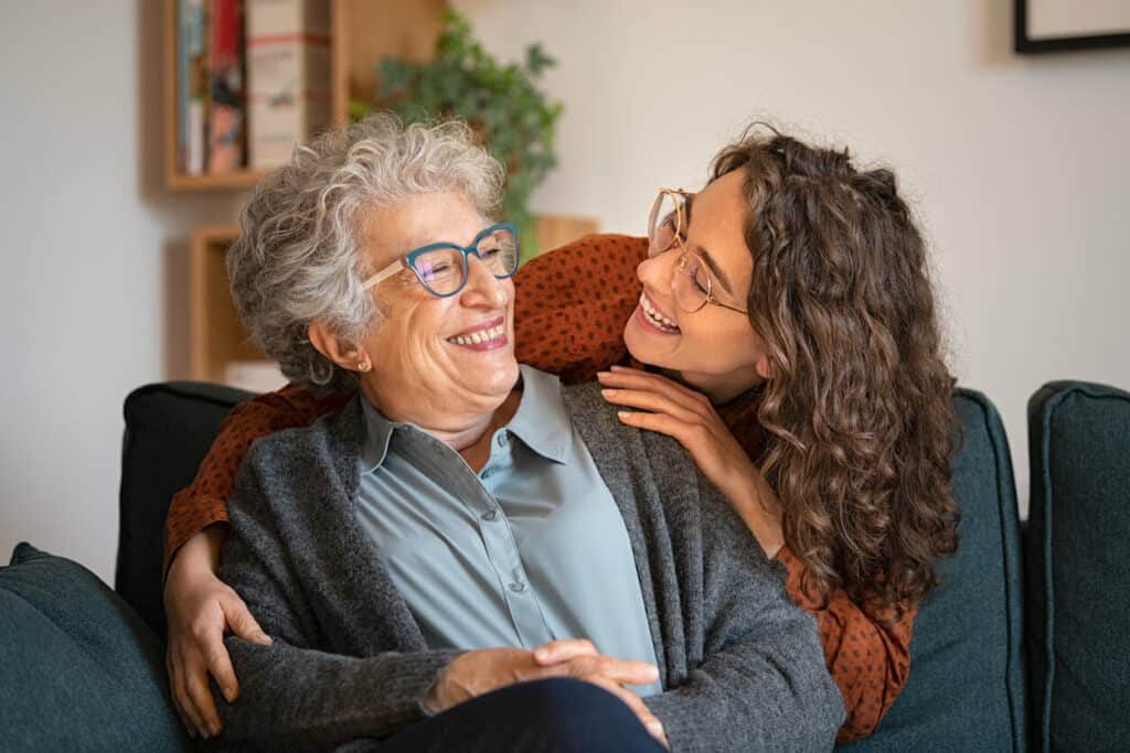 National joy day - grandmother and granddaughter laughing and embracing at home