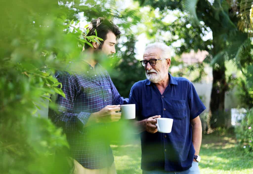An older man holding a cup of coffee and sharing quotes on age and wisdom to his son.