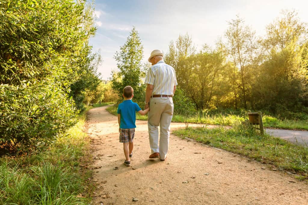 A senior man walking with his grandson talking about elderly quotes of wisdom.