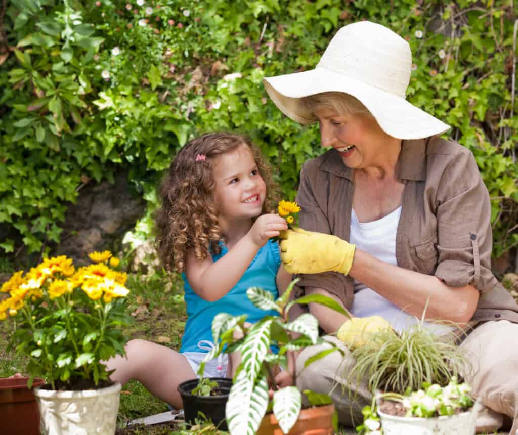 Quotes about age and wisdom - a happy grandmother planting flowers with her granddaughter in the garden.