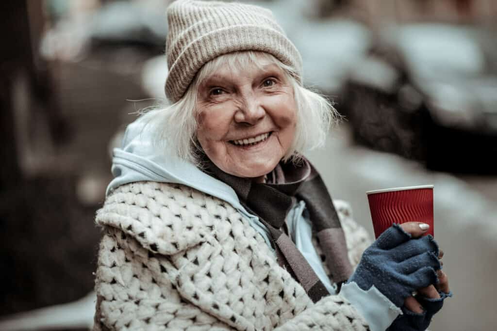 Quotes about age and wisdom - a smiling, cheerful senior woman holding a cup of coffee.