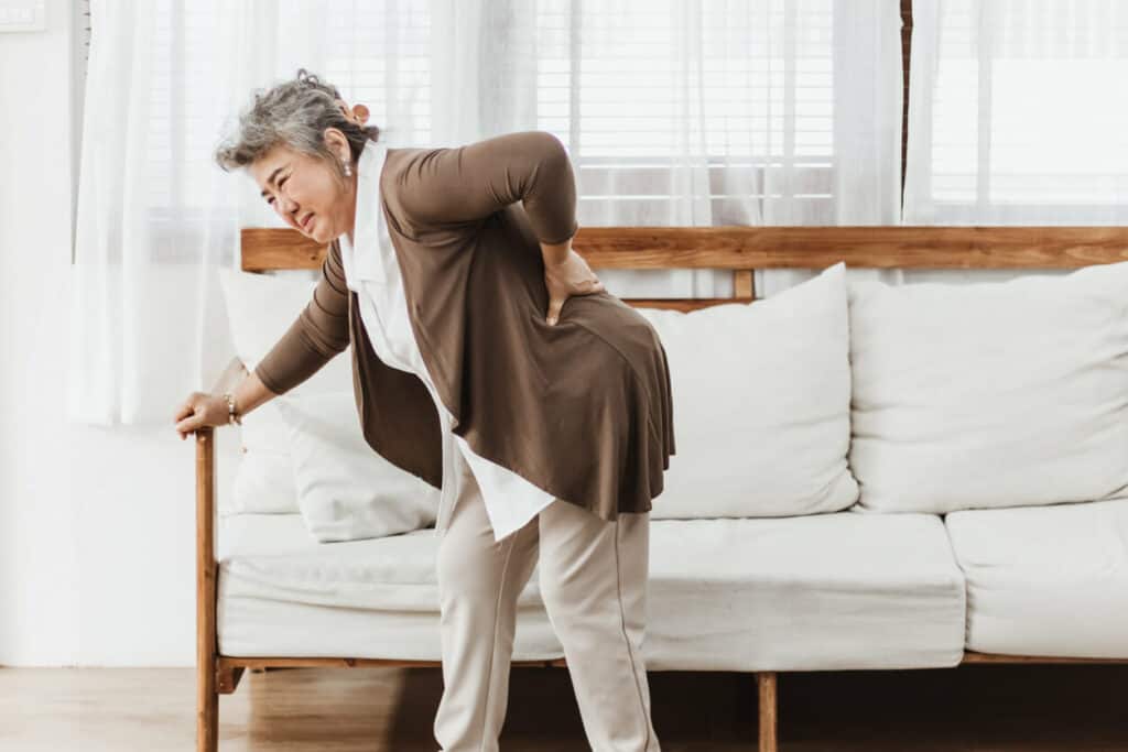 Elderly woman is bending with pain in her lower back She needs a geriatric massage