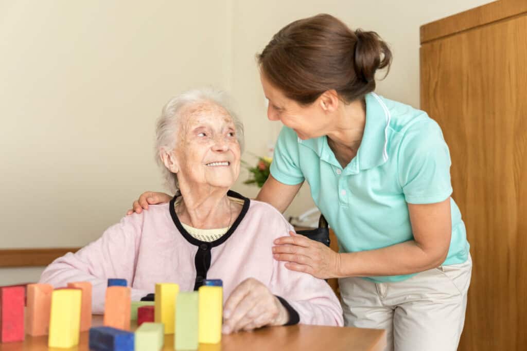A woman geriatric occupational therapist doing cognitive exercise with a senior woman with dementia.