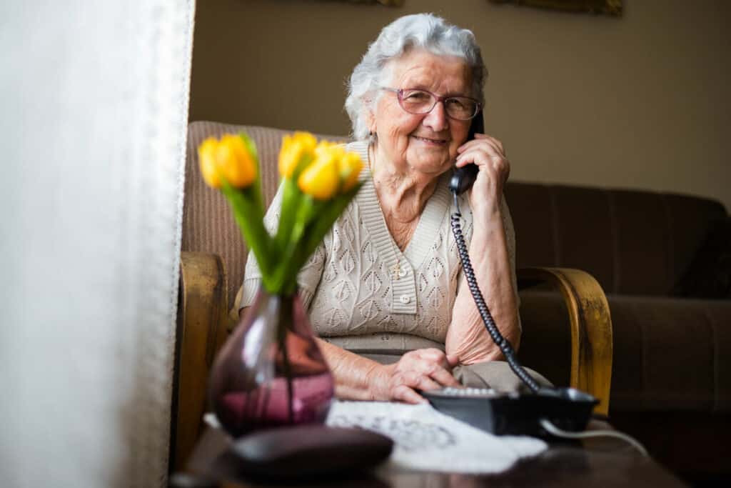 An older woman is talking to her family on the phone.