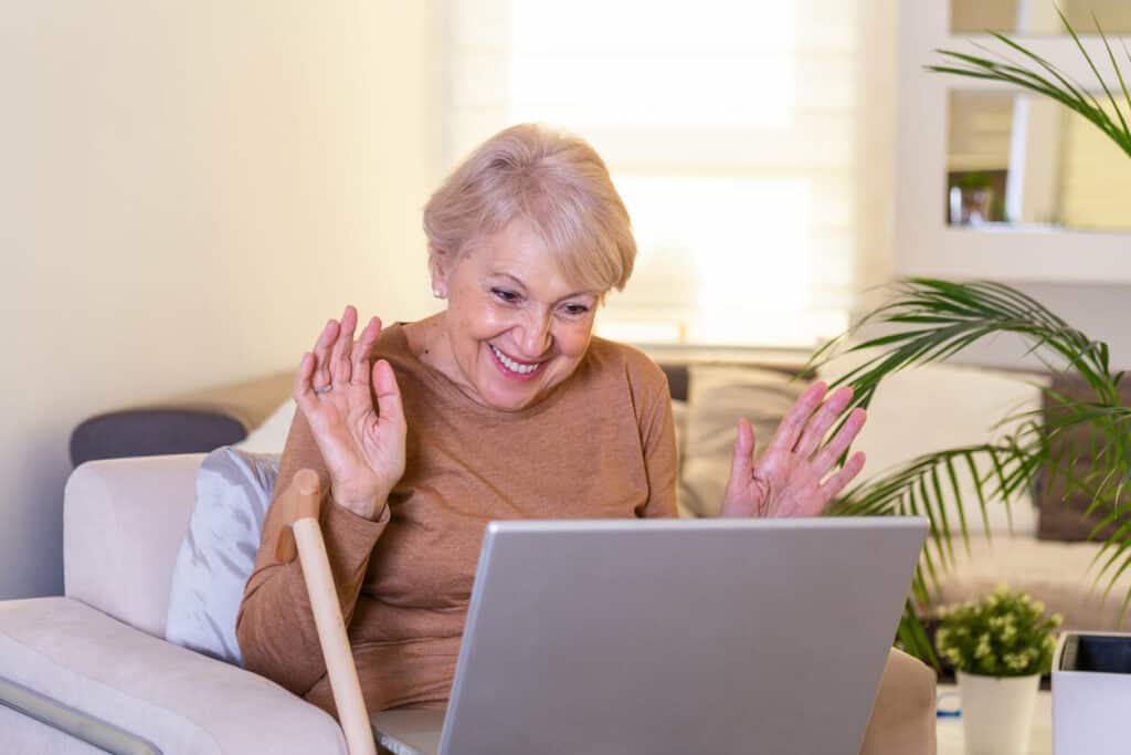 senior woman waving at their loving relatives on a video call without the need for tech support for seniors