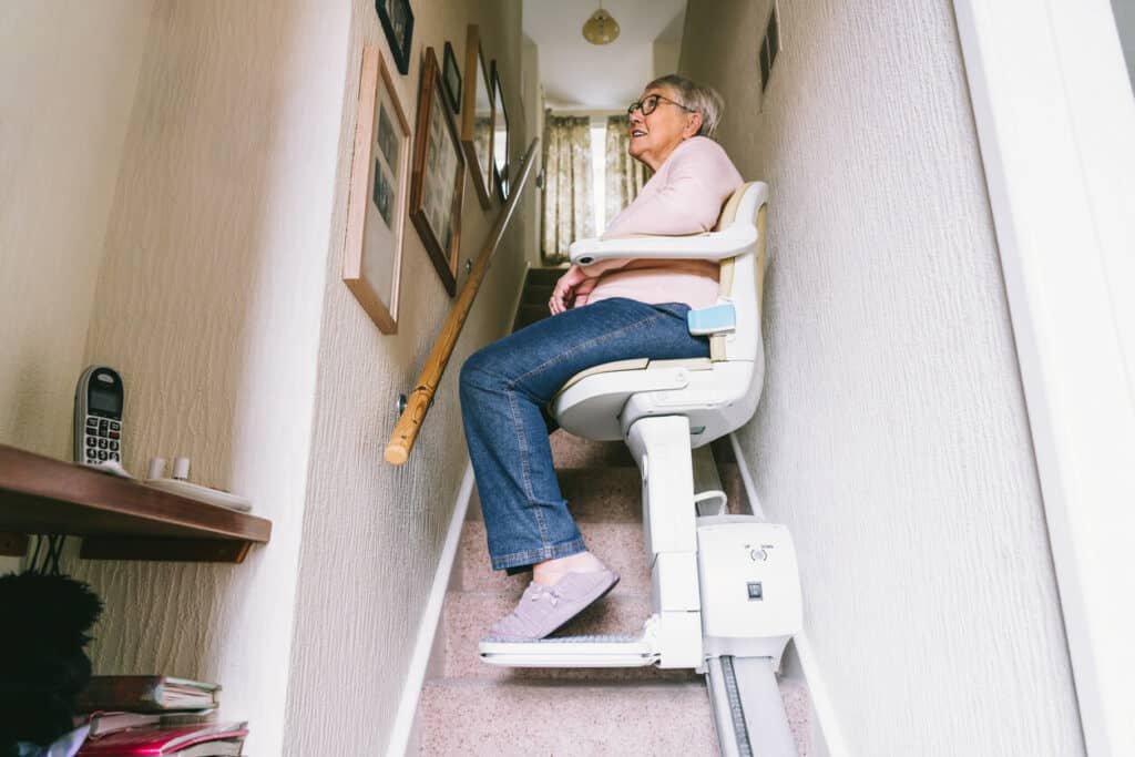 a senior woman using a stair lift at her house to move from one level to another