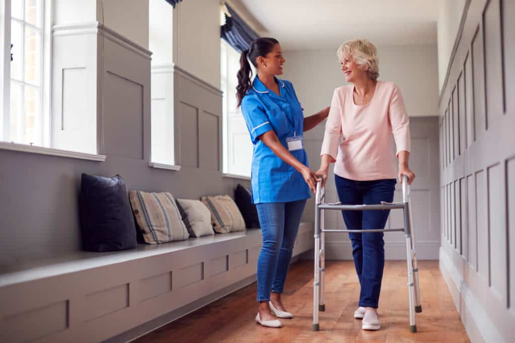 a female nurse assisting an older person with their walker