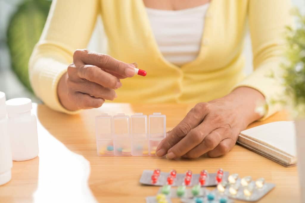 Older woman putting medication into boxes - acetaminophen for elderly
