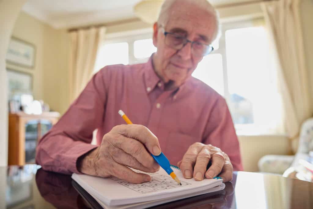 Older male learning using grip aid to hold a pencil - occupational therapy older adults