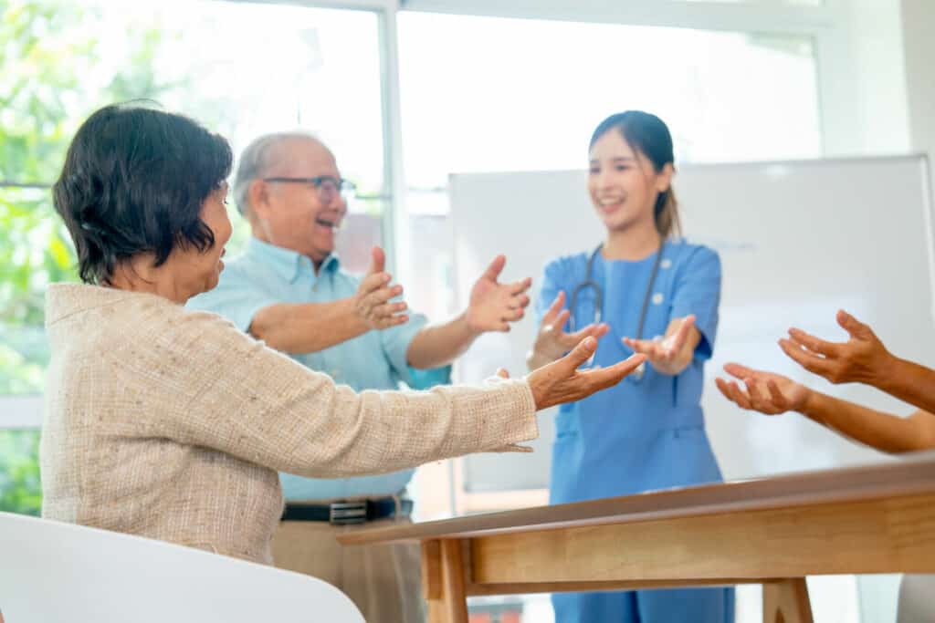 Female senior occupational therapist teaching older people some exercises
