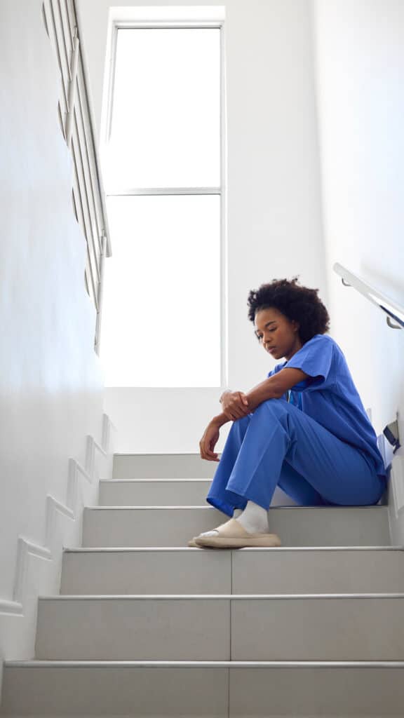 How to care for a caregiver - a burnout hospital caregiver sitting on stairs
