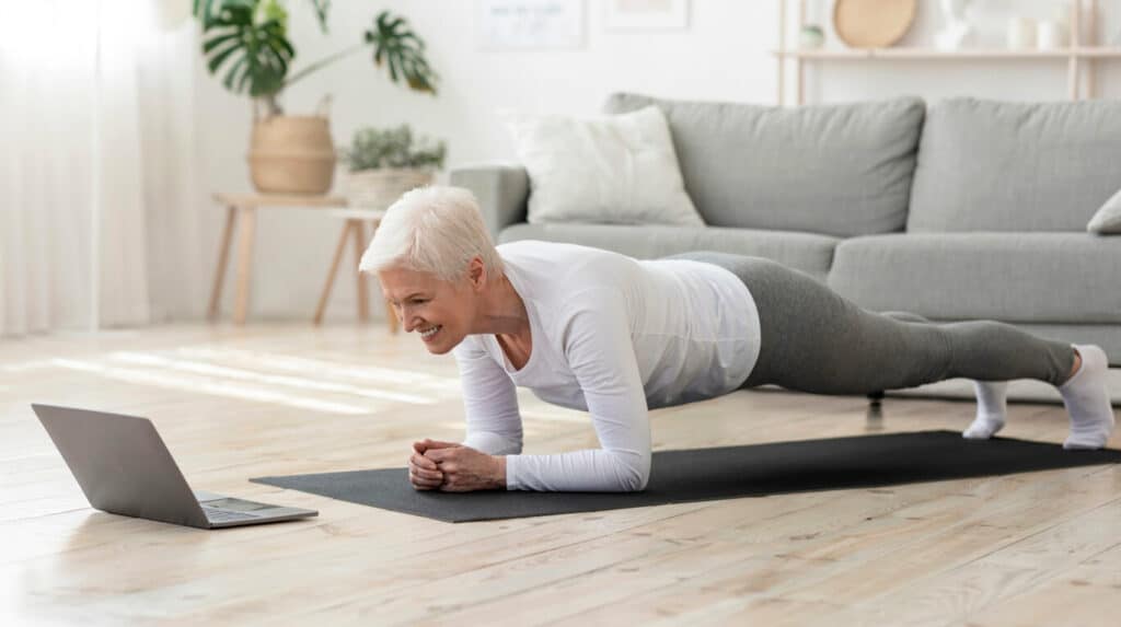 Senior exercise examples - a senior woman on a plank pose doing Pilates at home.