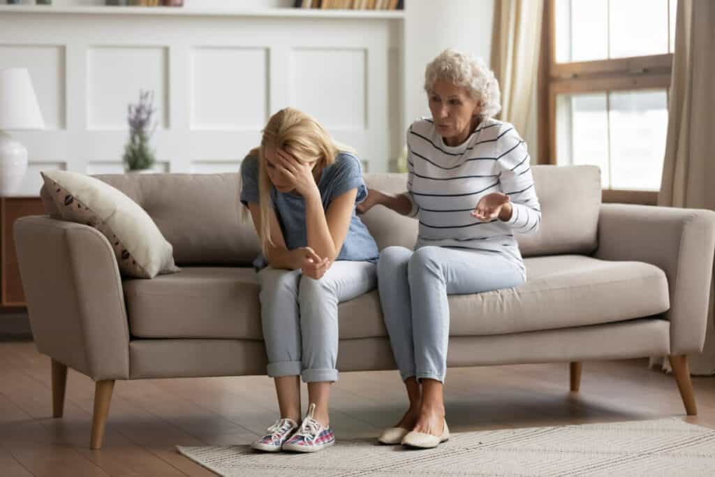 A senior woman lecturing her exhausted family caregiver who is also her daughter