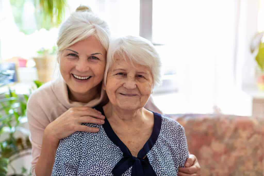 Caretaker fatigue - an adult family caregiver with her senior mom smiling happily to the camera.