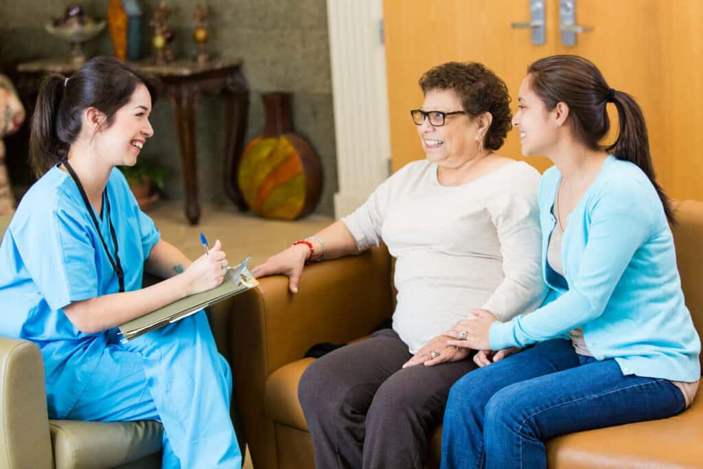 Caregiver burn out - a professional caregiver talking to a female family caregiver and her mom while taking notes.