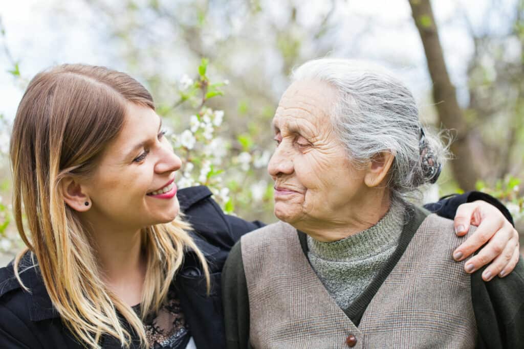 Caregiving for a family member - a caregiver who is helping her elderly mother enjoy springtime