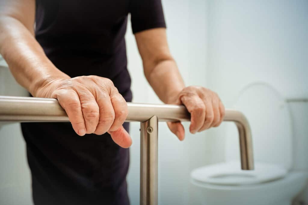 elderly woman holding on grab bars in the bathroom - dementia care tips